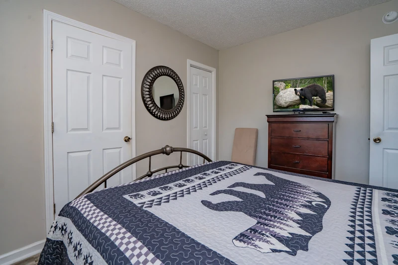 Your cozy bedroom awaits with a comfortable bed, stylish mirror, and warm wood furnishings that create a welcoming retreat after a day of adventure.