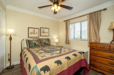 Settle into this cozy bedroom where warm wood tones and rustic charm welcome you. The gentle breeze from the ceiling fan and natural light from the window promise restful mountain mornings.
