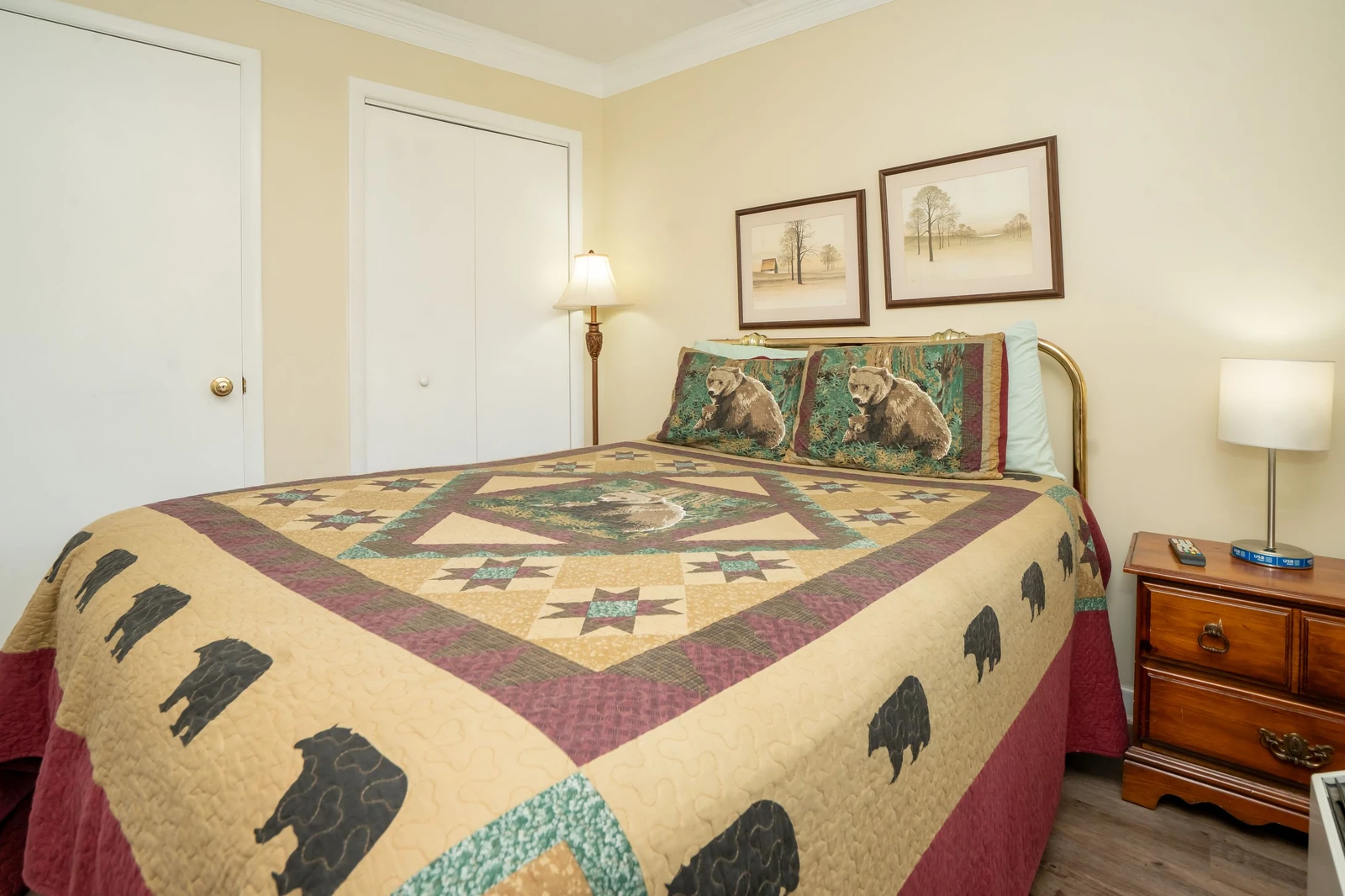 Your cozy retreat with warm tones, a charming quilt showcasing bears, and gentle lighting that creates a restful ambiance—perfect for unwinding after a day of adventure.