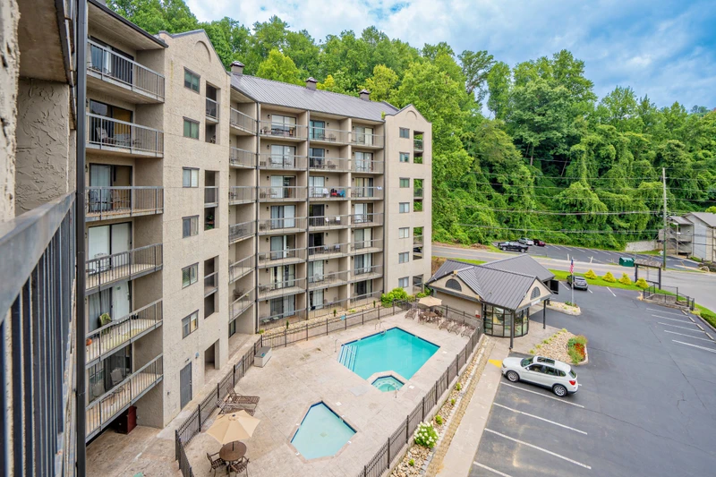 The property nestles against lush mountain greenery, with a pool and hot tub awaiting below. Spacious balconies overlook peaceful wooded surroundings, offering a tranquil mountain retreat.