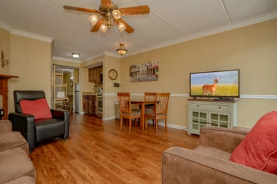 Cozy open-plan living and dining area with warm wood floors and comfortable seating. The dining table and nearby kitchen make this the perfect space for gathering and entertaining.