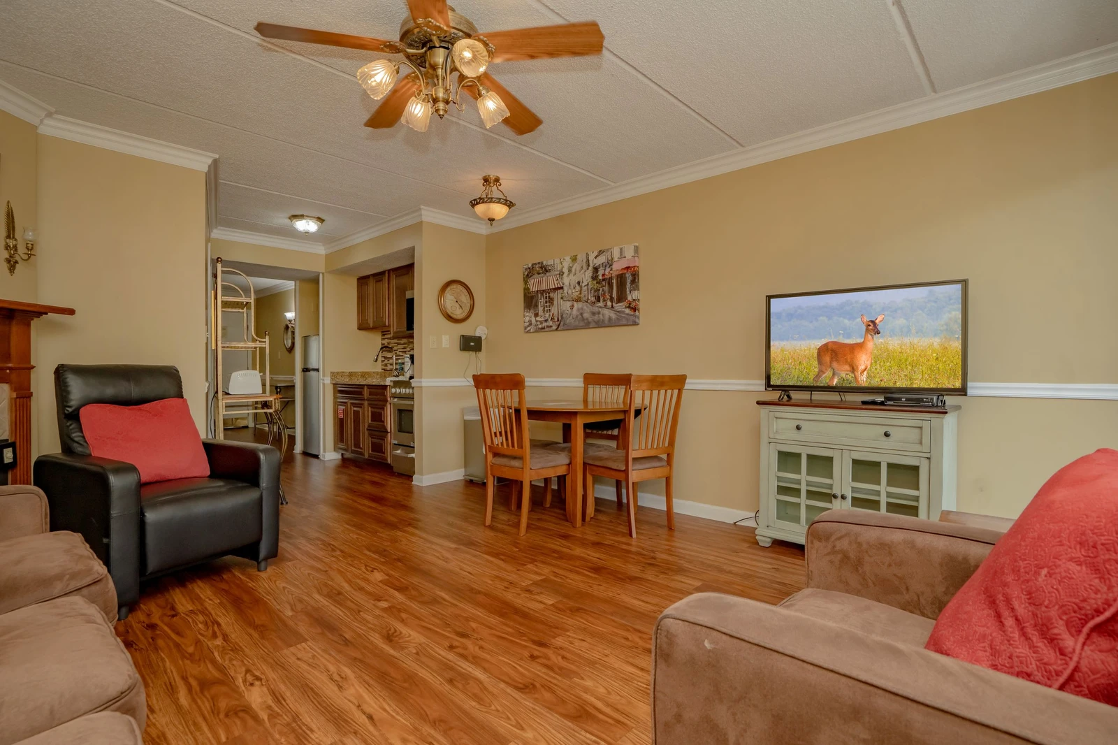 Cozy open-plan living and dining area with warm wood floors and comfortable seating. The dining table and nearby kitchen make this the perfect space for gathering and entertaining.