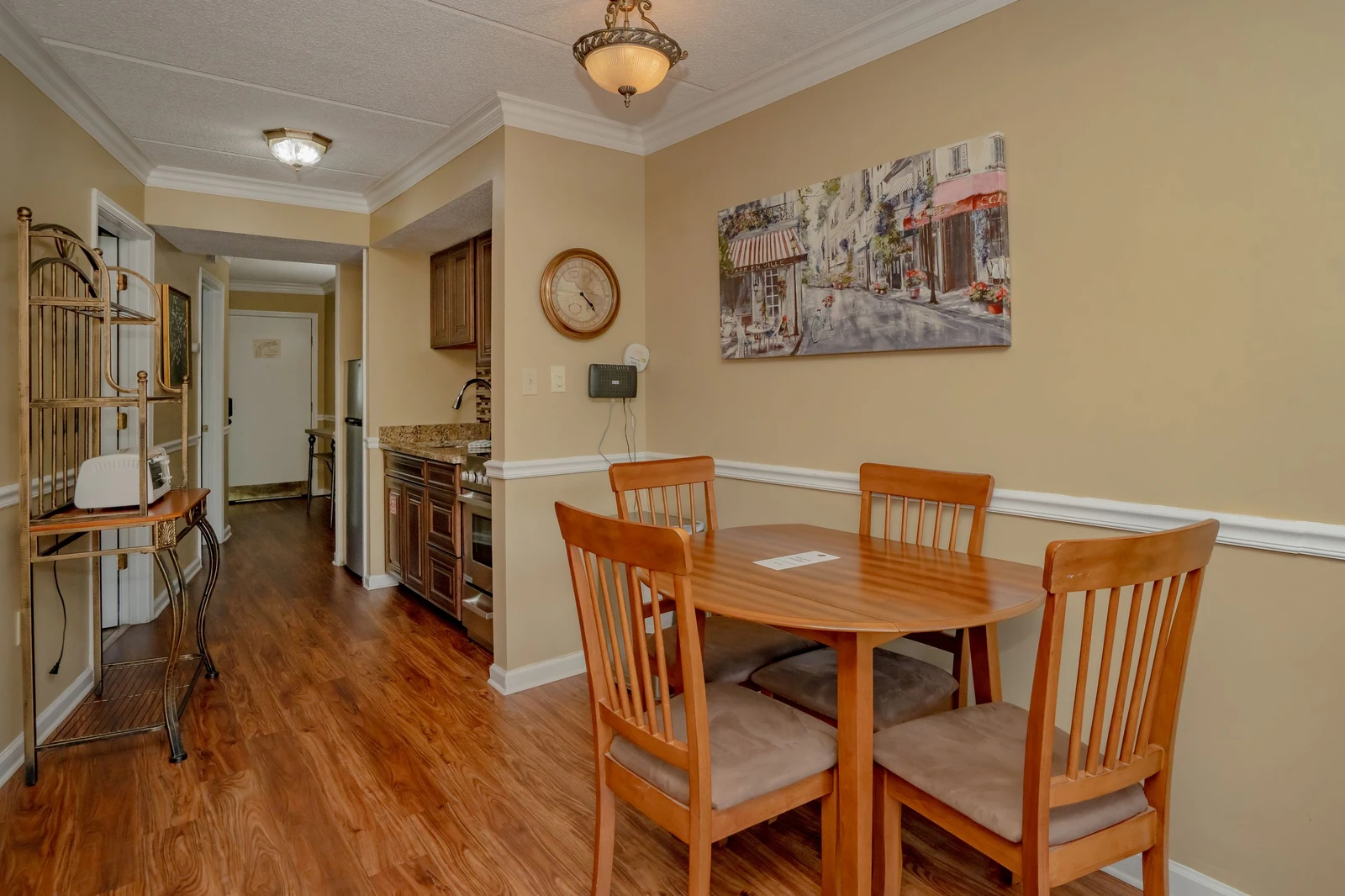 A welcoming dining area where you can share meals at a warm wood table for four, with rich hardwood floors underfoot and elegant lighting above.
