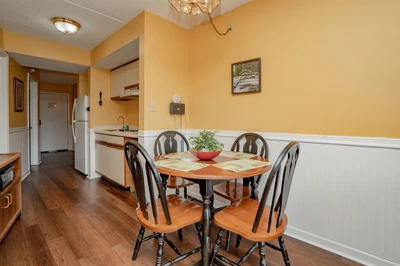 Gather around this welcoming dining table in your cozy kitchen space, warmed by golden walls and natural light—perfect for morning coffee or sharing meals with loved ones.