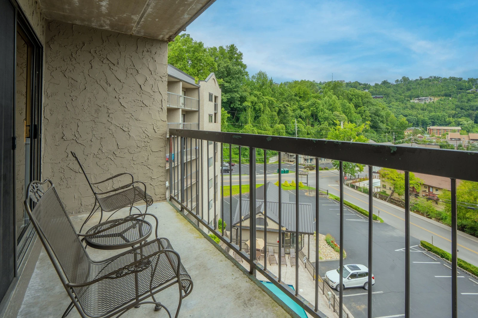 Step out onto your private balcony and take in the peaceful hillside views—lush green trees frame the horizon while comfortable seating invites you to relax with your morning coffee or unwind after a day of exploring.