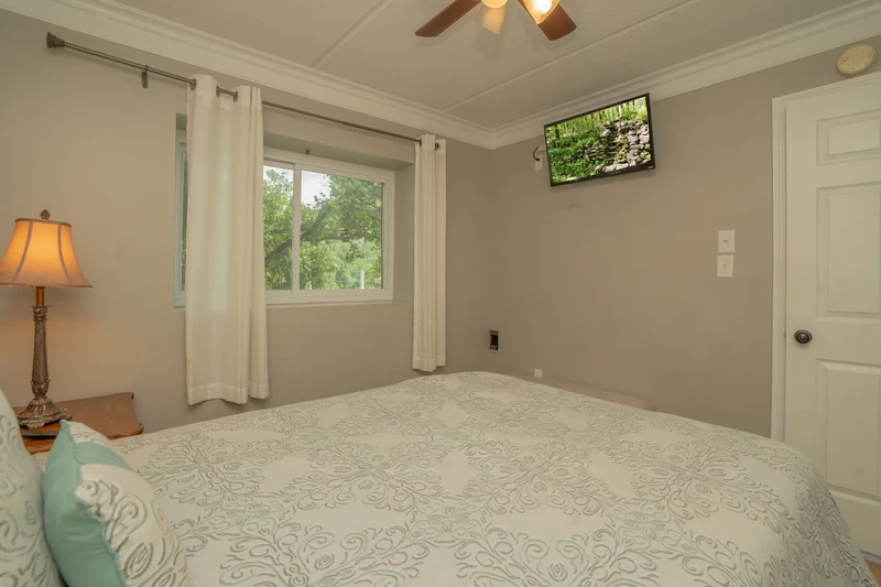 Unwind in your peaceful bedroom with views of the lush surrounding greenery. The ceiling fan keeps you comfortable, and a TV is ready for relaxing evenings in.