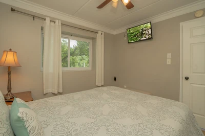 Unwind in your peaceful bedroom with views of the lush surrounding greenery. The ceiling fan keeps you comfortable, and a TV is ready for relaxing evenings in.