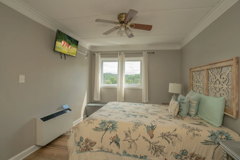 Wake up to natural light streaming through dual windows overlooking lush greenery. Your serene retreat features a ceiling fan to keep you comfortable and charming coastal decor for a peaceful escape.