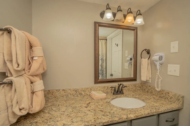 Slip into your robe and enjoy a well-appointed bathroom featuring granite countertops, warm lighting, and thoughtful touches like a hair dryer and plush towels ready for you.