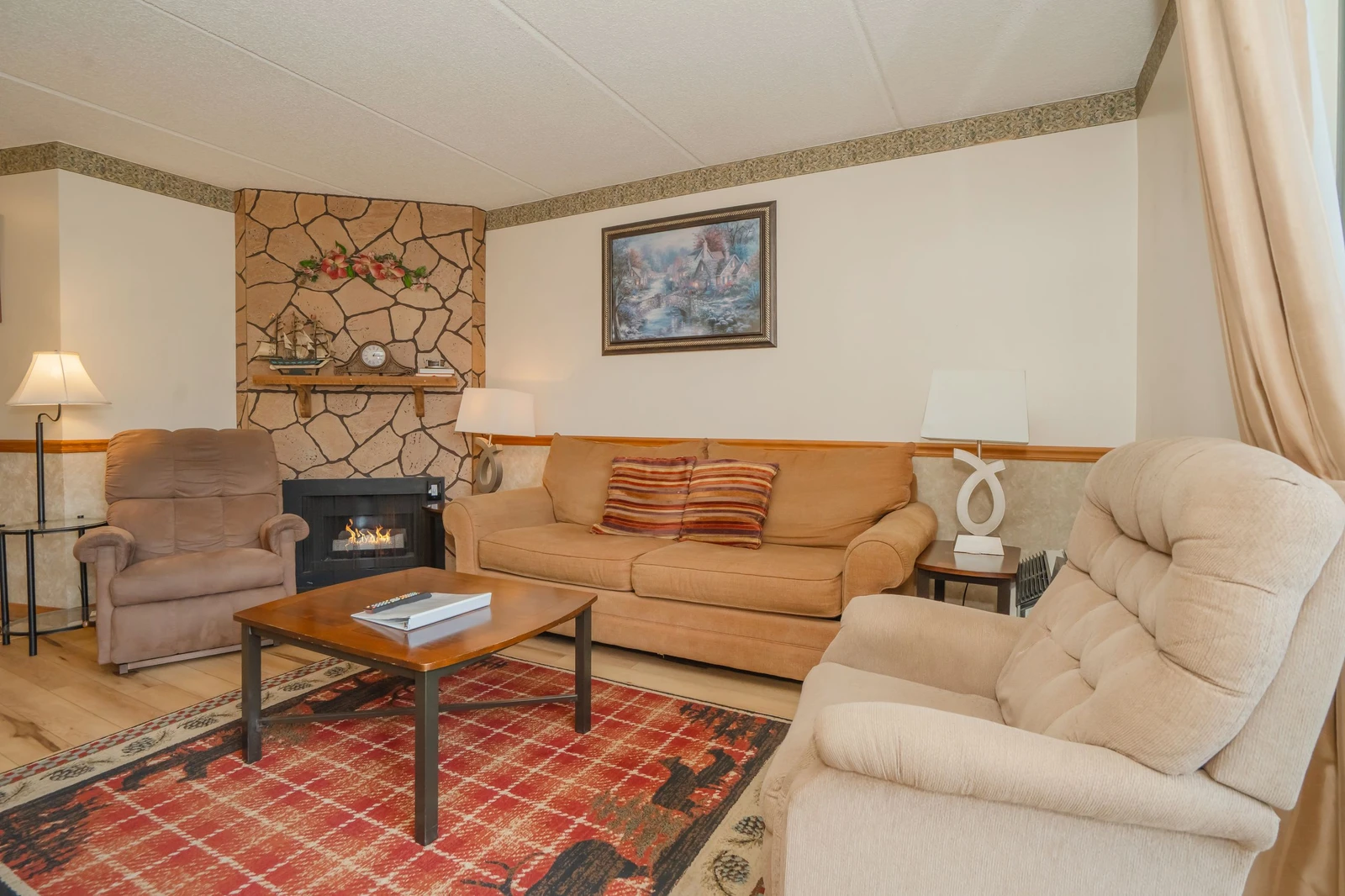 Gather around the warm fireplace and sink into plush seating in your cozy living room. The stone hearth adds rustic charm, while soft lighting creates the perfect atmosphere for relaxing evenings.