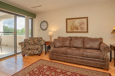 Settle into this inviting living space where you'll find plush seating and warm hardwood floors. Natural light pours through the balcony door, creating the perfect spot to unwind after your daily adventures.