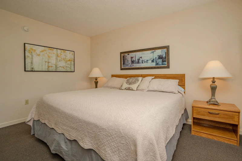 Your peaceful bedroom retreat features a plush king bed, warm ambient lighting, and coastal artwork that sets a soothing tone for restful nights.