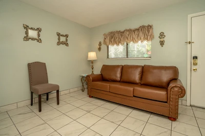 Settle into this inviting living room where a classic leather sofa and cozy chair await your arrival. Natural light filters through the window, creating a welcoming retreat for your stay.