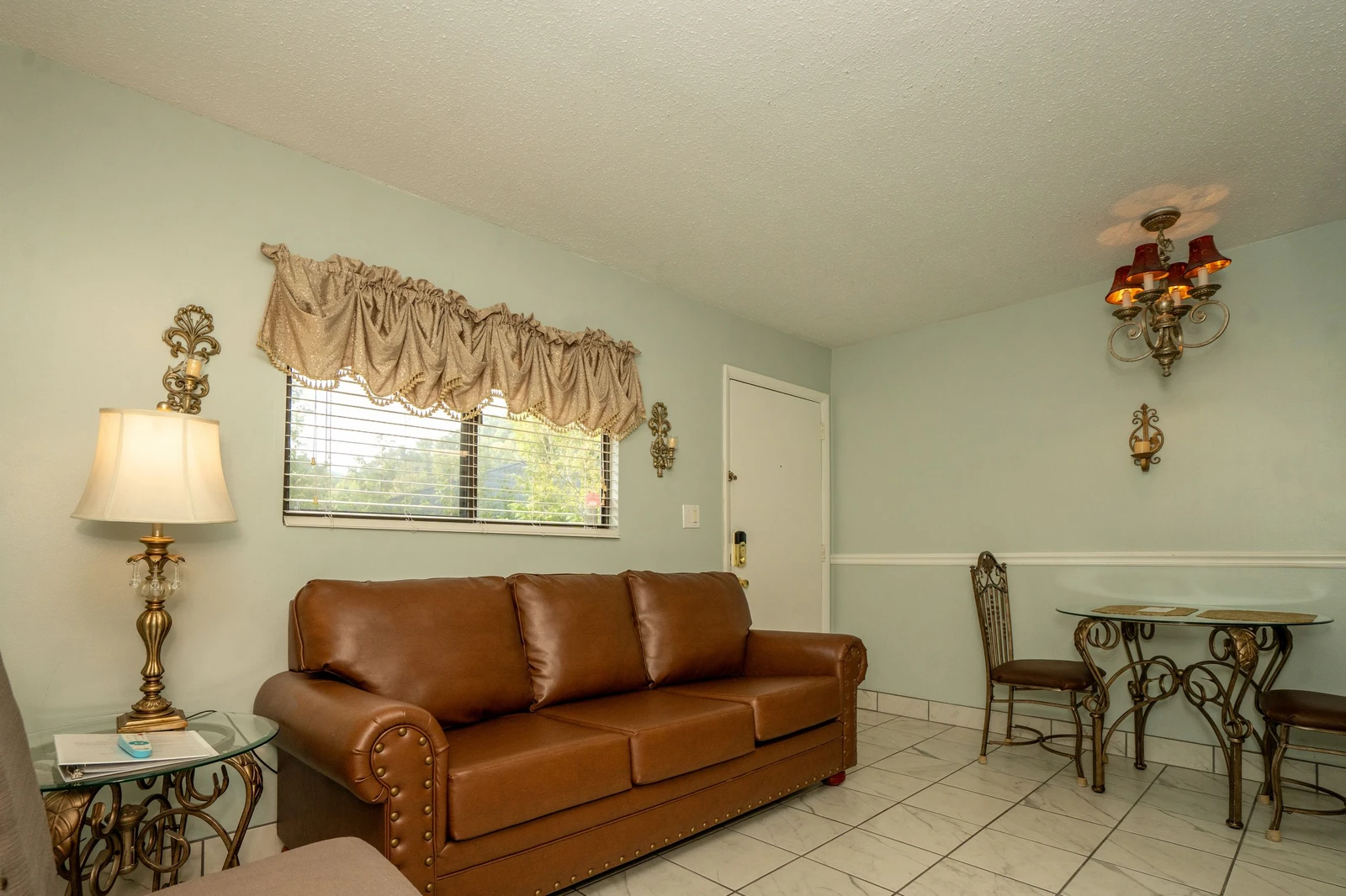 Step into your inviting living space, where a comfortable leather sofa and charming dining nook await your arrival. Natural light fills the room, creating a warm and welcoming retreat for your stay.