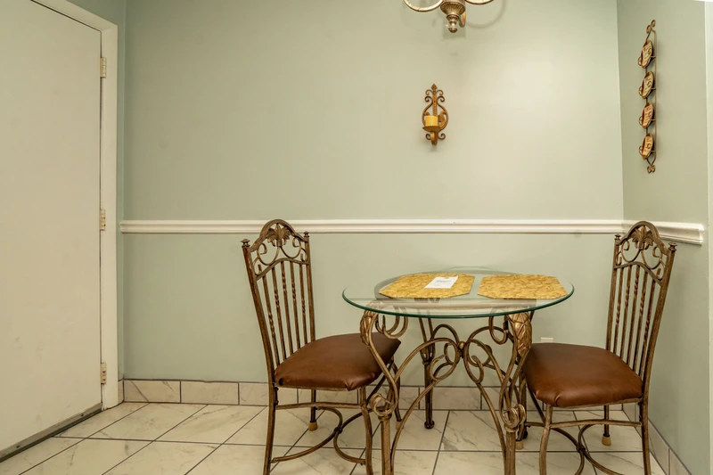 A cozy breakfast nook with elegant wrought-iron furniture and soft mint walls creates your perfect morning coffee spot.