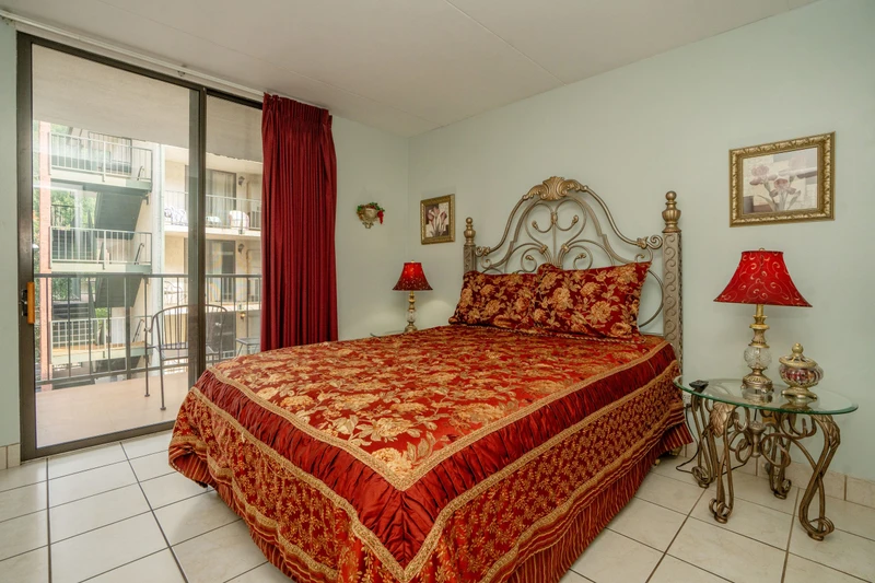 Step into your elegant bedroom retreat with an ornate headboard, rich red-and-gold bedding, and charming decor that creates a warm, regal atmosphere perfect for restful nights.