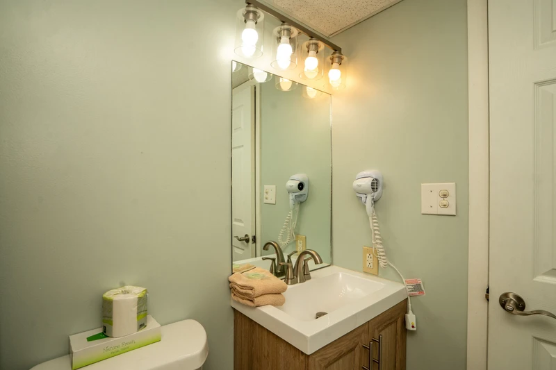 Your private bathroom features crisp lighting, a modern vanity, and thoughtful touches like fresh towels and a convenient hair dryer—ready for you to settle in and refresh.