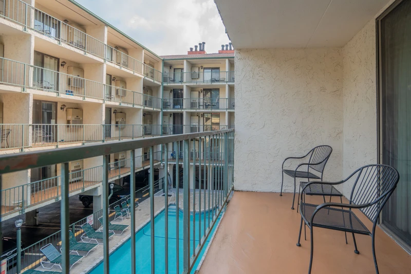 Your private balcony offers a peaceful spot to relax with a morning coffee, overlooking the central courtyard and sparkling pool below. Settle into the outdoor seating and soak in the quiet ambiance of this inviting retreat.