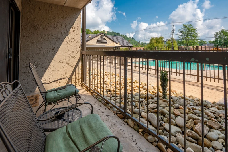 Step out onto your private balcony and relax in the fresh mountain air while soaking in views of the sparkling pool below, framed by natural stone landscaping.