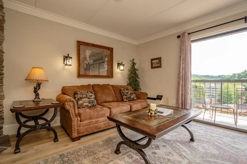 Sink into the plush sofa and unwind in your cozy living space, where rustic charm meets comfort and sweeping views of green fields stretch beyond your private balcony.