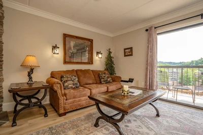 Sink into the plush sofa and unwind in your cozy living space, where rustic charm meets comfort and sweeping views of green fields stretch beyond your private balcony.