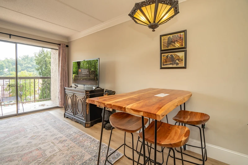 This inviting living and dining space features a stunning live-edge wood table where you can share meals or morning coffee. Natural light fills the room, while your private balcony offers peaceful views of the surrounding greenery.