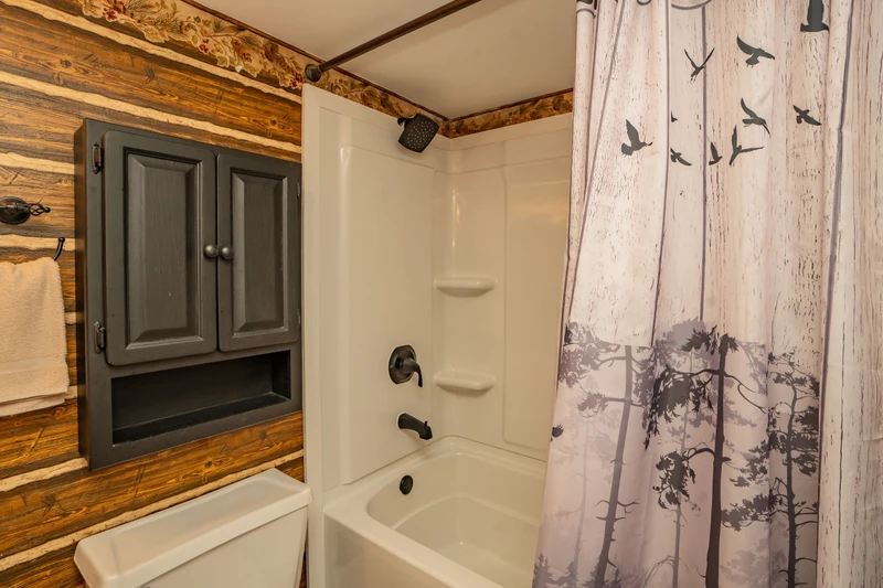 Freshen up in your cozy rustic bathroom, where charming wood-paneled walls meet modern comfort for a relaxing mountain retreat experience.