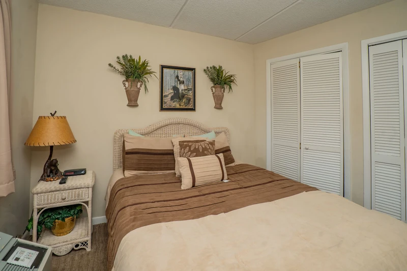Sink into this cozy bedroom with its plush bedding and tropical touches. Your restful retreat awaits, complete with ample closet space and warm coastal charm.