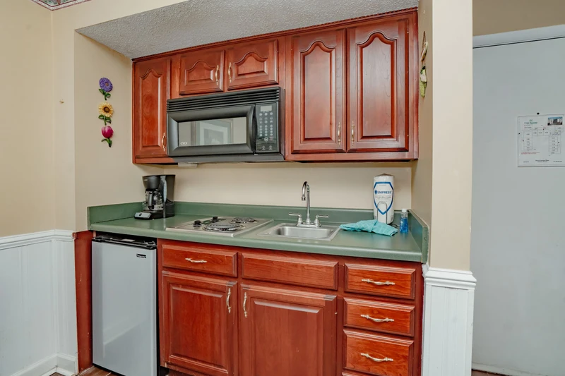 Your fully equipped kitchenette features warm wood cabinetry, a stove, microwave, and everything you need to prepare light meals during your stay.