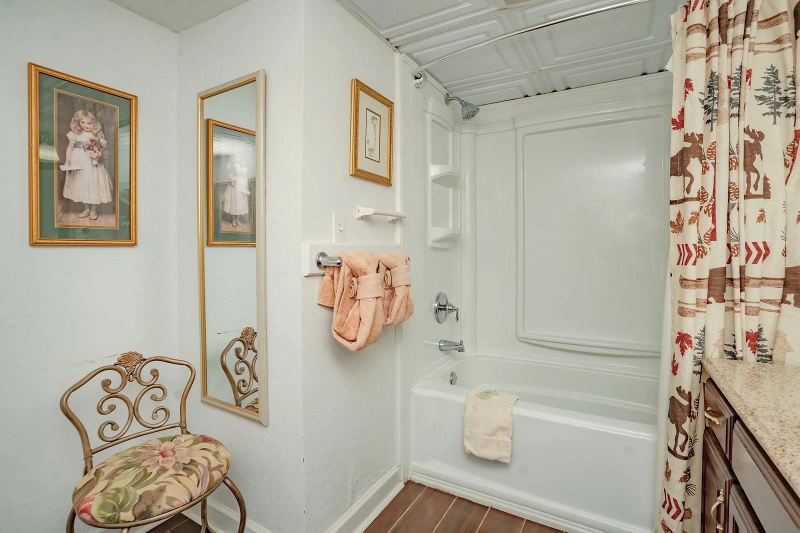 Step into your cozy bathroom with a fresh tub-shower combo, soft towels ready for you, and charming vintage-style décor that makes every moment feel like home.