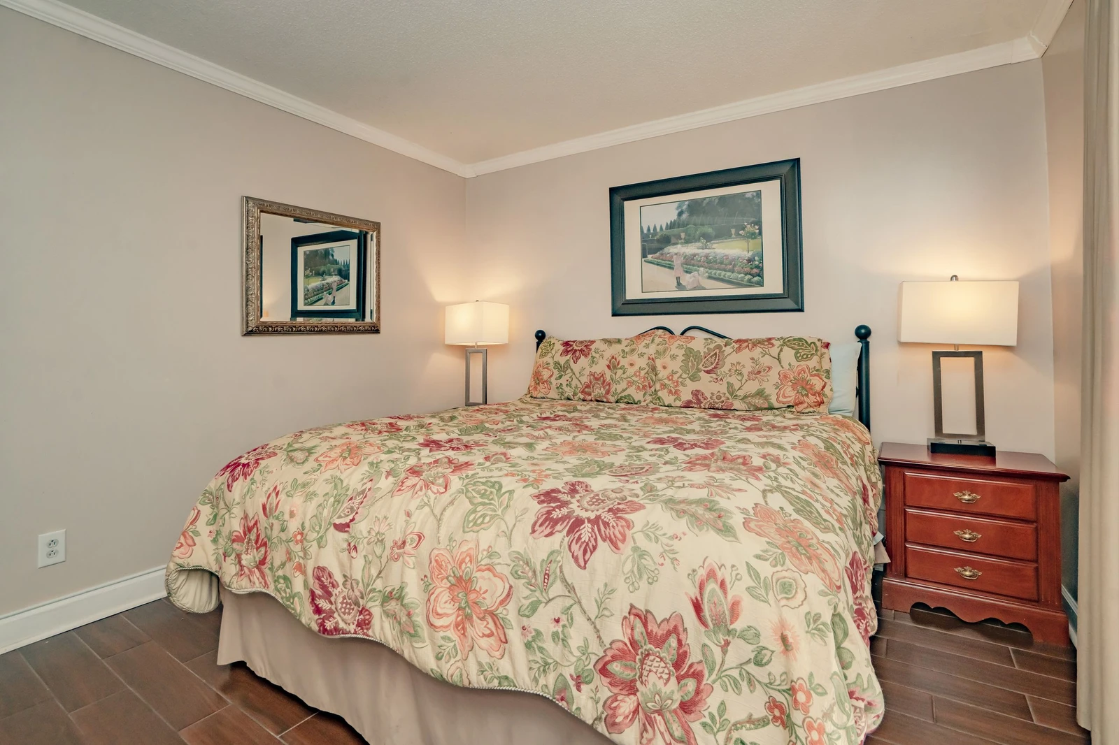 Settle in for a restful stay in this cozy bedroom featuring a welcoming bed dressed in soft florals and nightstands with warm reading lamps at your side.
