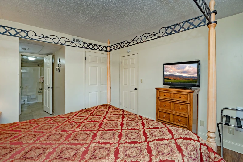 Your spacious bedroom offers comfortable sleeping quarters with a classic canopy frame, dresser, and flat-screen TV—plus an ensuite bath just steps away for your convenience.
