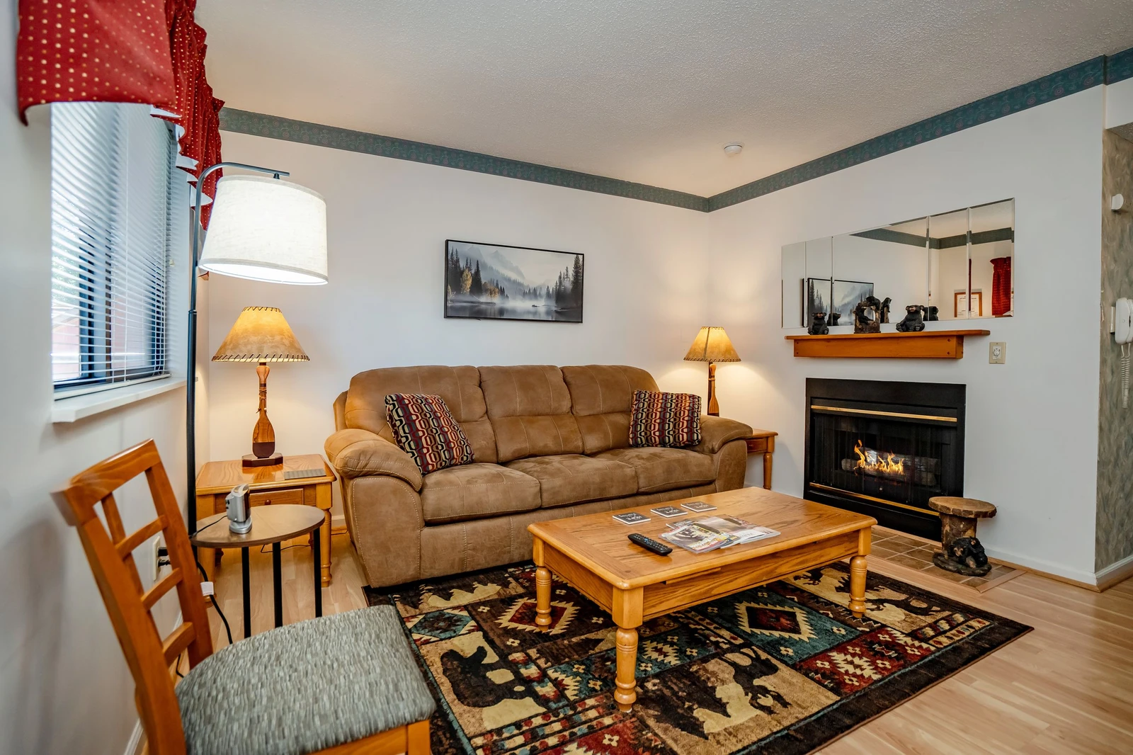 Settle into your cozy living space featuring a warm fireplace, plush sofa, and natural light streaming through the windows—your perfect retreat after a day of mountain adventures.