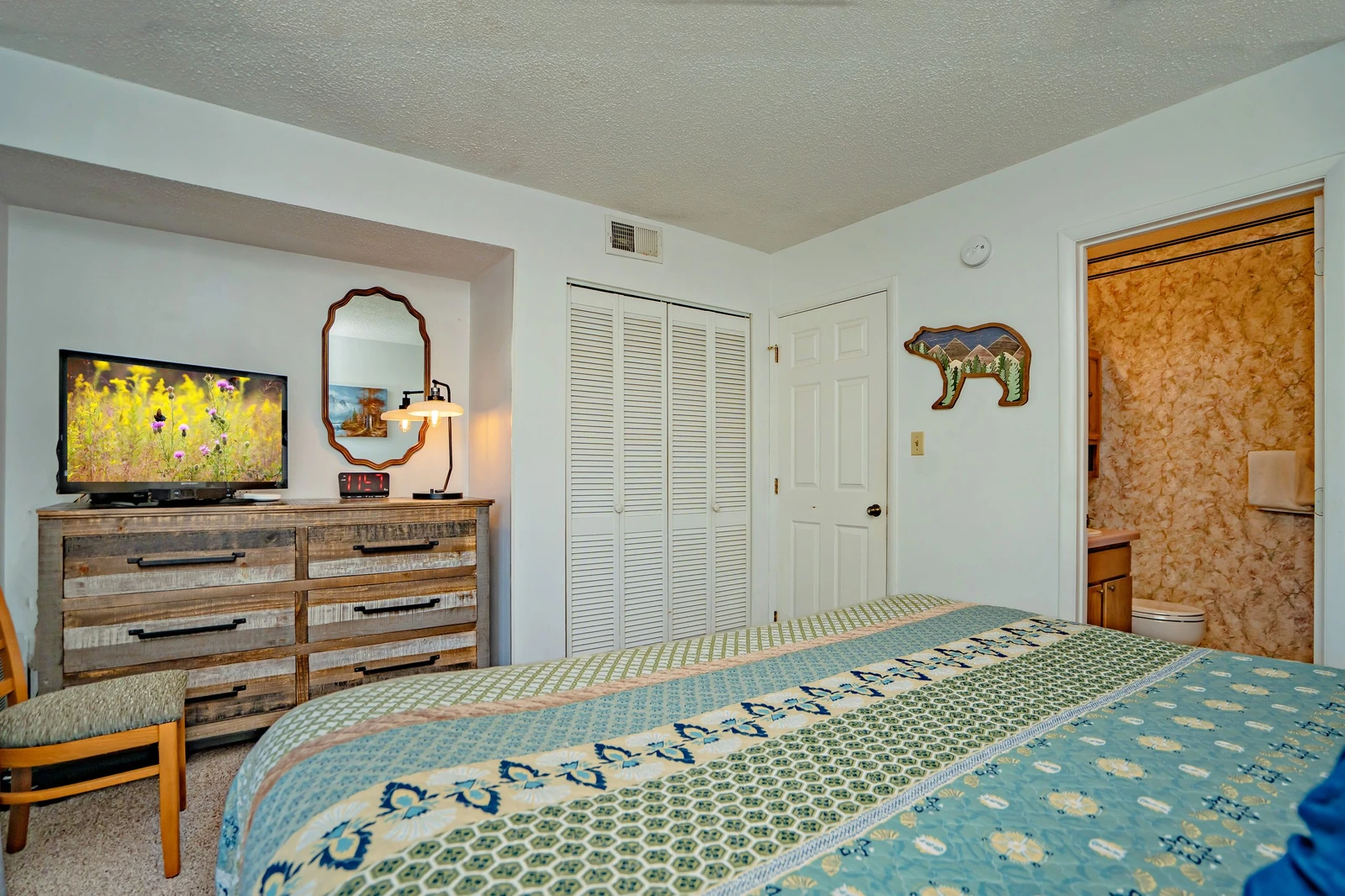 Unwind in this cozy bedroom with rustic charm, featuring a comfortable bed, entertainment setup, and your own private bathroom just steps away.