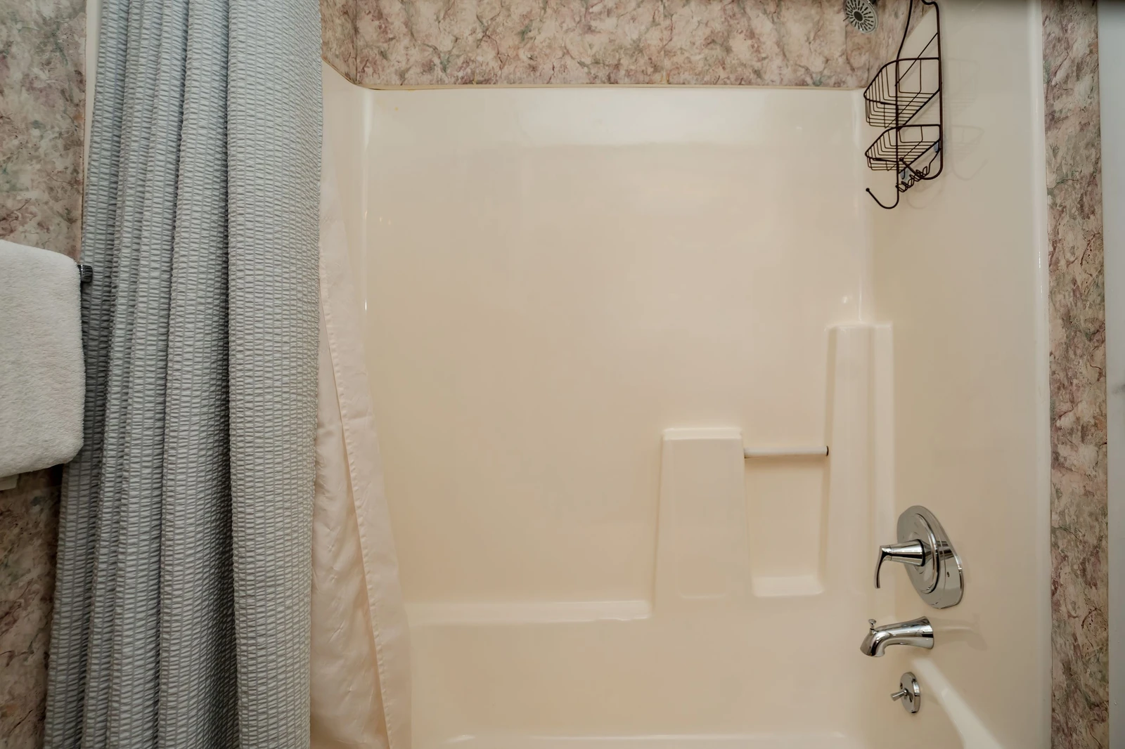 Your private bathroom features a pristine tub and shower combo, wrapped in warm marble-toned walls that create a cozy retreat for unwinding after the day's adventures.