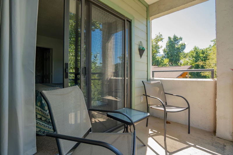 Step onto your private balcony and unwind in the fresh air, where comfortable seating invites you to enjoy peaceful moments surrounded by lush greenery and treetop views.