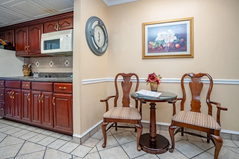 Enjoy your morning coffee at the charming bistro table, perfectly positioned between the fully equipped kitchen and your cozy dining nook. Classic wood furnishings and warm tones create a welcoming space that feels like home.