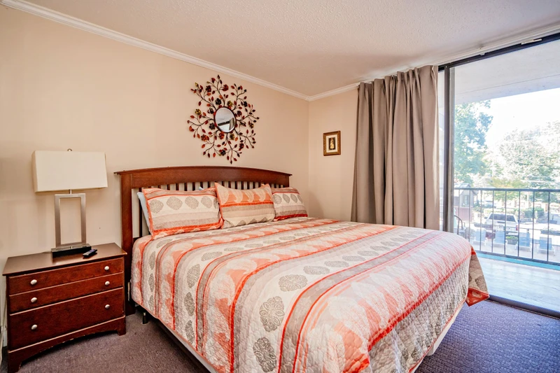 Drift off in your serene bedroom featuring a plush bed dressed in soft linens and a warm color palette. Natural light pours in from your private balcony, framing peaceful views of the surrounding neighborhood.