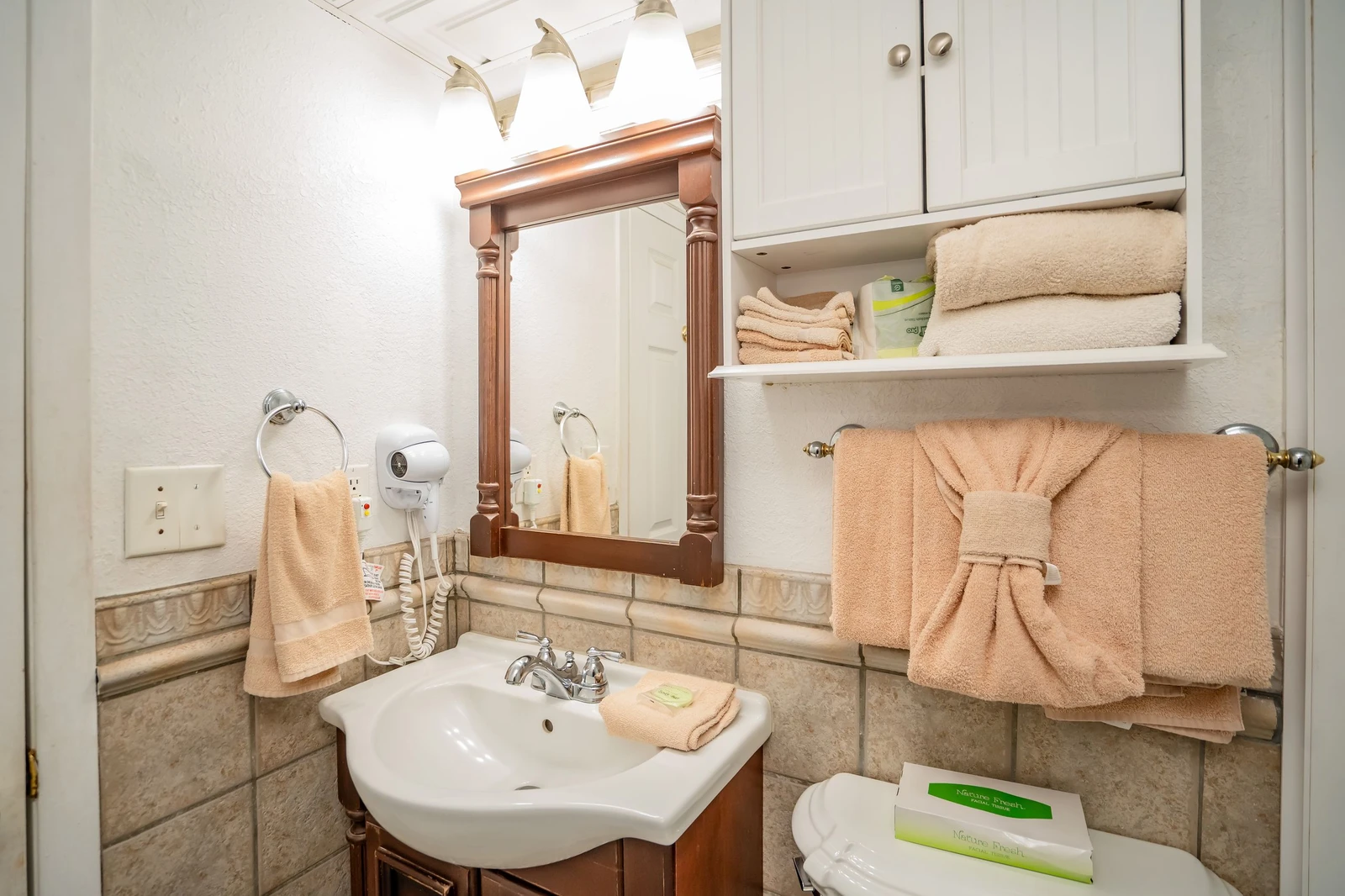 Step into your private bathroom, where fresh towels await and thoughtful touches make you feel right at home. Classic tile and warm wood tones create a cozy, polished retreat.