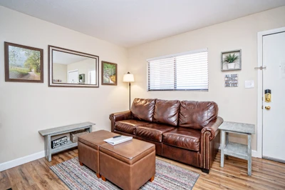 Sink into plush leather seating in your cozy living room, where warm wood tones and natural light create the perfect spot to unwind after exploring.