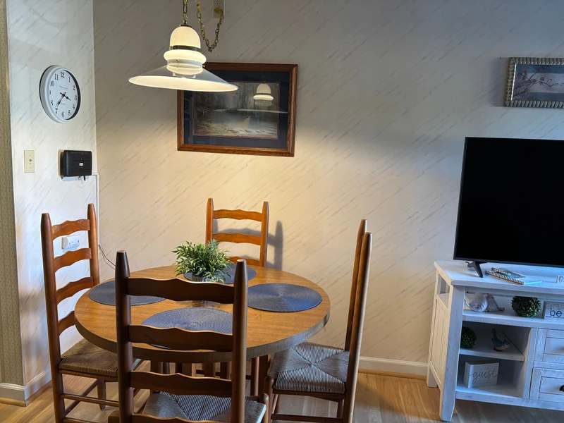 Your cozy dining nook awaits with a charming round table set for four, bathed in warm pendant lighting. Enjoy meals together in this inviting space with wood floors and thoughtful touches throughout.